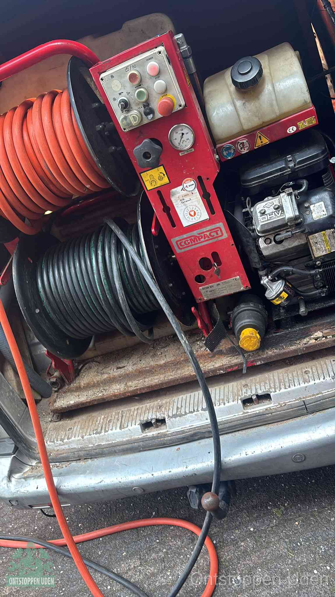 Een rood hogedruk-rioolreinigingstoestel in de laadbak van de bedrijfsbus, apparatuur voor een hardnekkige afvoerverstopping in Uden