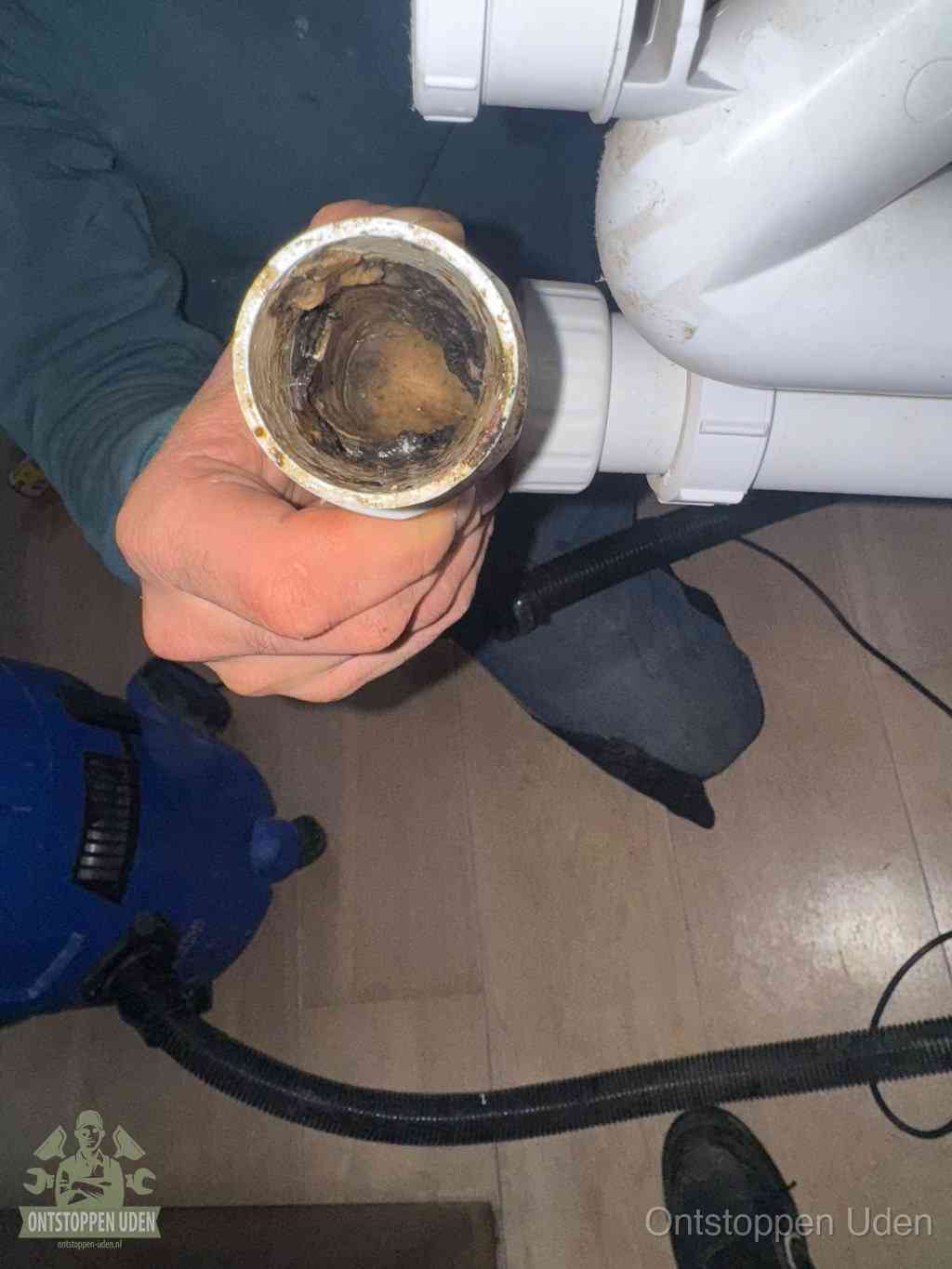 Een losgekoppelde afvoerbuis die van binnen volledig is dichtgeslibd met vet en aanslag, de meest voorkomende oorzaak van een verstopte gootsteen in Uden