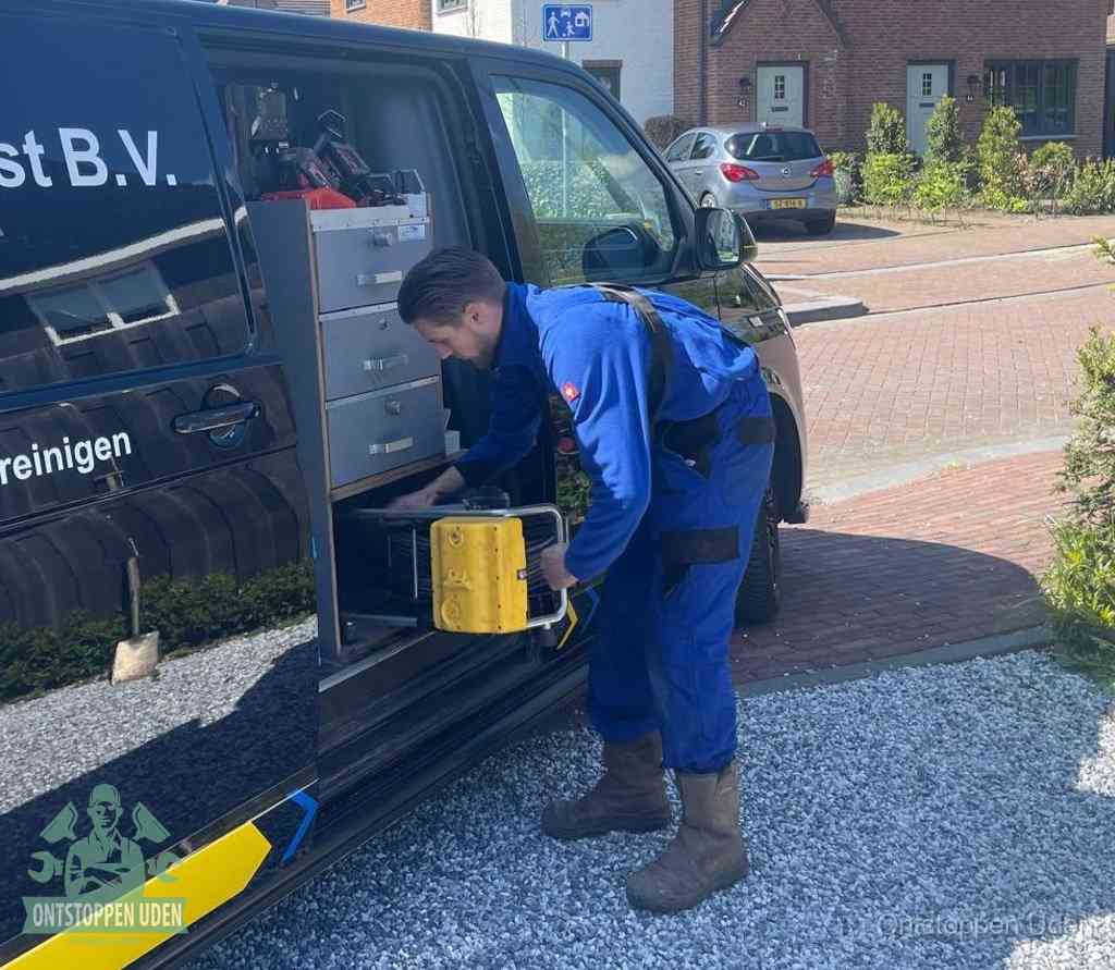Een monteur pakt buiten op de oprit gereedschap uit de bedrijfsbus, het moment om een professional in te schakelen voor een verstopte afvoer in Uden
