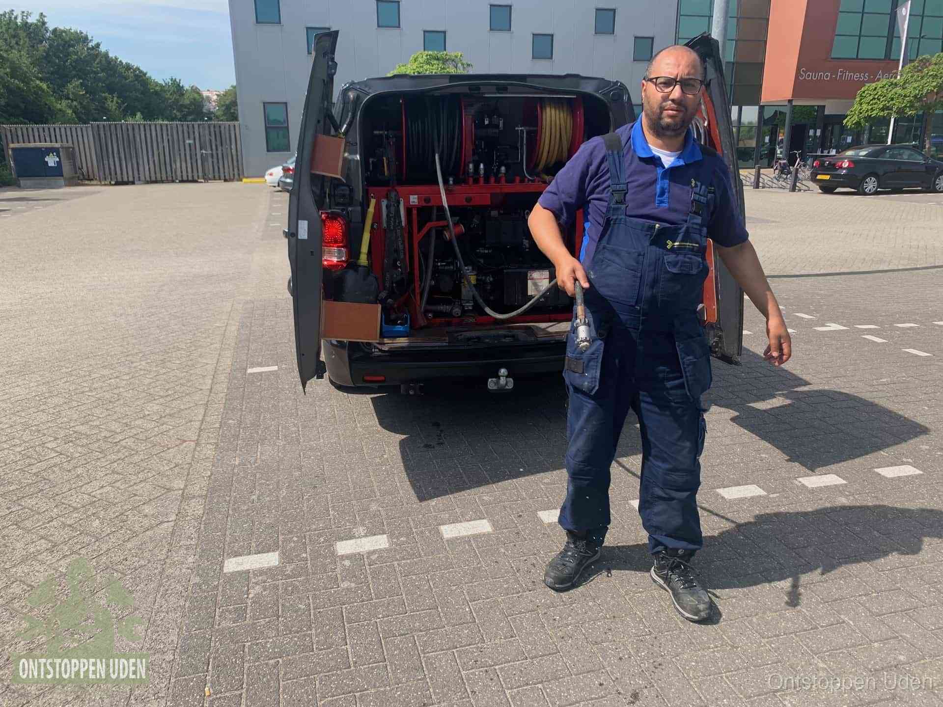 Een monteur bij zijn bestelbus met een hogedruk- en rioolreinigingsunit, klaar om de oorzaak van terugkerende wc-verstoppingen aan te pakken in Uden