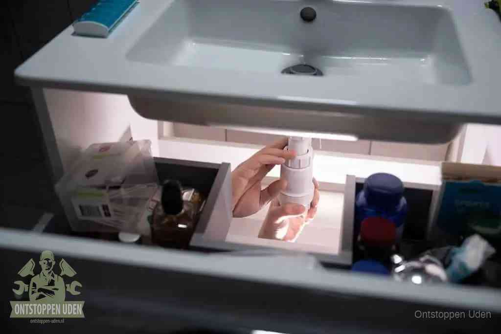 Een pompfles met zeep boven een wastafel in de toiletruimte, de warm water en afwasmiddel-methode om de wc te ontstoppen in Uden
