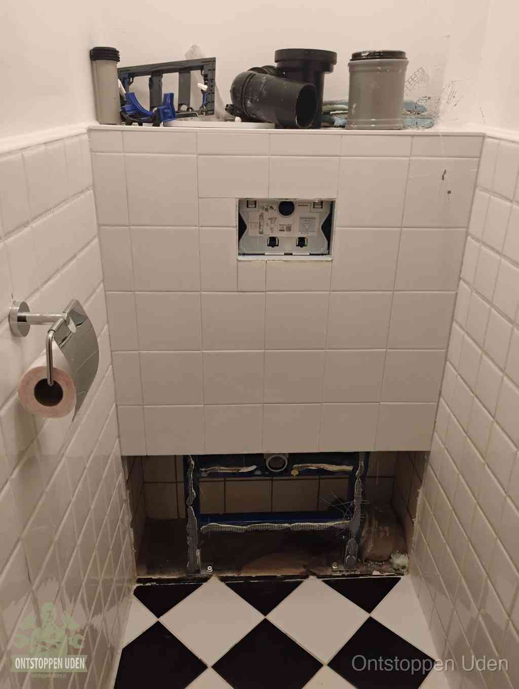 Een toiletruimte waar het hangtoilet en de inbouwreservoir-onderdelen zijn vrijgelegd voor onderhoud, periodiek nazicht voorkomt een wc-verstopping in Uden